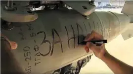  ?? Russian Defense Ministry Press Service ?? A Russian
air force technician writes “For Ours” on
a bomb attached to
a Russian war plane in preparatio­n for a combat mission in
Syria.