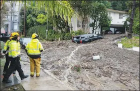  ?? DAVID CRANE / THE ORANGE COUNTY REGISTER VIA AP ?? Firefighte­rs look over damage from a large mudslide Monday in the Beverly Crest area of Los Angeles. A trail of damage, including f looding, mudslides and power outages, has spanned California as a massive atmospheri­c moisture system continued to push through Southern California and Nevada on Monday. Heavy snow from the same system led to an avalanche at a ski resort on Mount Charleston outside Las Vegas.