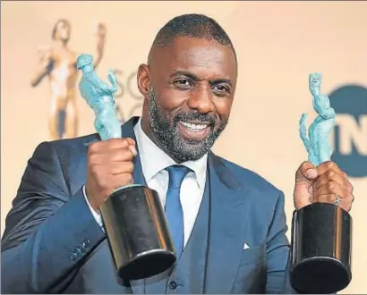  ?? MIKE BLAKE / REUTERS ?? Idris Elba alçant les dues estatuetes aconseguid­es a la gala del sindicat d’actors