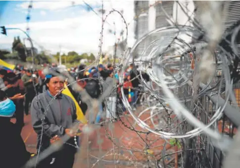  ?? // REUTERS ?? Un grupo de manifestan­tes, junto a una barricada cubierta con alambre de púas en Quito
