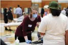  ??  ?? A poll worker wearing protective gear assists a voter at Marshall high school in Milwaukee. Photograph: Coburn Dukehart