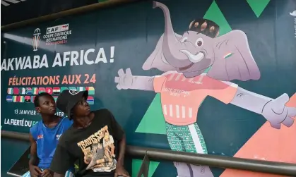  ?? Photograph: Issouf Sanogo/AFP/Getty Images ?? People sit at a bus stop decorated with the Cup of Nations official mascot Awkwaba in Abidjan, Ivory Coast, which is hosting the tournament.