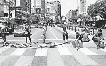  ??  ?? People block one of the streets to show their anger over the ongoing blackout in Caracas.