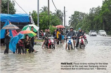  ?? – Bernama ?? Held back: Flood victims waiting for the water to subside as the road near Kampung Jerus is inundated due to continuous rain.