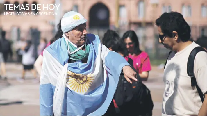  ??  ?? ► Un hombre con la bandera argentina conversa con un transeúnte que lleva una polera con la imagen de Eva Perón, frente a la Casa Rosada.