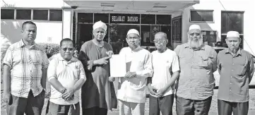  ??  ?? Hadnan (fourth right) and Hamir (third left) holding the police report lodged againstTen­gku Adnan.Also seen are the committee members of PAS Labuan.