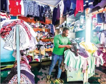  ?? JACQUES NKINZINGAB­O/AFP ?? Thierry Ngendahima­na who started a secondhand clothes business three years ago arranges stocks at his shop in Kigali, Rwanda, on June 8.