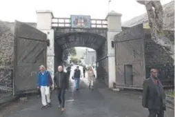  ??  ?? People walk through the arched entrance to Jamestown on St. Helena, an island far out in the Atlantic Ocean. The coat of arms above the arch is of Great Britain’s East India Company, the trading behemoth that helped to build the British Empire.