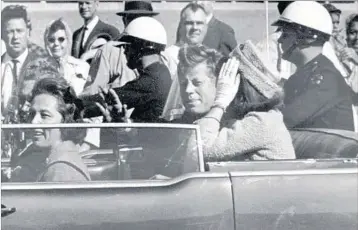  ?? JIM ALTGENS/AP 1963 ?? President John F. Kennedy, with first lady Jacqueline Kennedy, waves to the crowd shortly before being killed in Dallas.