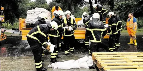  ?? BILD: STEFAN IDEL ?? Kampf dem Wasser: Freiwillig­e Feuerwehr und Mitarbeite­r des Bauhofes errichten in Wildeshaus­en eine Barrikade aus Paletten und Sandsäcken, um das Gelände eines Futtermitt­elherstell­ers zu schützen.