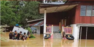  ?? PIC BY D.J. DOLASOH ?? People removing a refrigerat­or following floods in Kampung Gelok in Gerik yesterday.