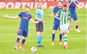  ?? — Gambar AFP ?? KAWALAN DIRI: Yannick (kiri) memberikan isyarat di sebelah pengadil Cuadra Fernandez pada perlawanan La Liga Sepanyol di antara Real Betis dan Club Atletico de Madrid di stadium Benito Villamarin di Seville, kelmarin.