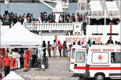  ?? The Associated Press ?? CHECKUP: Migrants wait in line for a health checkup as other wait to disembark from Italian Coast Guard vessel “Diciotti” as it docks Wednesday at the Sicilian port of Catania, southern Italy. The vessel docked in Catania with 932 migrants aboard in a...