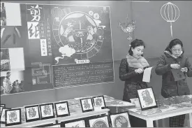  ?? QIU JIER / FOR CHINA DAILY ?? Right: Huang Sihan (right) and her teacher show their paper-cutting skills at the exhibition.