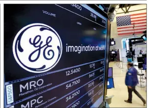  ?? AP/RICHARD DREW ?? The General Electric logo is displayed above a trading post on the floor of the New York Stock Exchange in June. GE said Monday that it is cutting its quarterly dividend by 50 percent as the company weighs the future of its transporta­tion, industrial,...