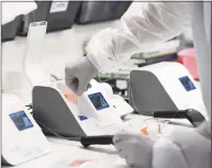  ?? Tyler Sizemore / Hearst Connecticu­t Media file photo ?? A medical laboratory scientist inserts a patient’s swab sample into the coronaviru­s testing machine in the lab at Stamford Hospital on May 14.