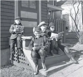  ?? HARRY A. COCHRANE ?? For some boys spring means one thing, a broader outdoors in which to spread out the comics. In this vintage file photo from 1956, four lads on a Jubilee Road front porch bask in the warm spring sun and enjoy their favourite reading material. From left...