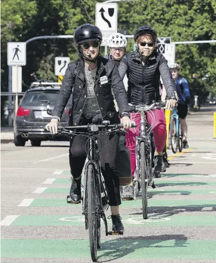  ?? DAVID BLOOM ?? City project manager Olga Messinis, front, and bike education co-ordinator Dot Laing ride along 100 Avenue near 109 Street Thursday during a preview of the first leg of the city’s downtown bike grid.