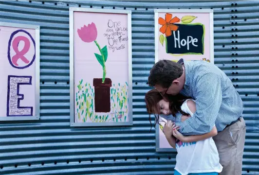  ?? FILE PHOTO BY DOUG STRICKLAND ?? Above: Marshall Wood hugs his daughter Haley on Sept. 11, 2012, in front of the Texarkana Regional Arts and Humanities Council’s Art Wall during at an unveiling ceremony for paintings created by breast cancer survivors or family members who have lost loved ones to breast cancer. Wood lost his mother to breast cancer, and Haley made a painting on the wall in her honor.