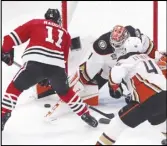  ?? Associated Press ?? Ducks goaltender Lukas Dostal makes a save against the Blackhawks’ Taylor Raddysh as the Ducks’ Ilya Lyubushkin also defends during the first period, Thursday, in Chicago.