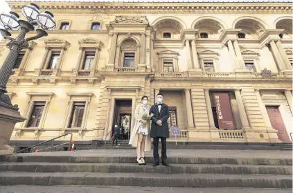  ?? PHOTO: GETTY IMAGES. ?? Newlyweds . . . Rob and Reno (no surname given) pose for a photograph outside the Victorian Marriage Registry after their wedding yesterday in Melbourne. Retail stores across the city will close to customers today as further stage 4 lockdown restrictio­ns are implemente­d in response to Victoria’s ongoing Covid19 outbreak. The new rules come into effect at 11.59pm today (local time). Businesses will be able to operate click and collect services with social distancing and contactles­s payments. Supermarke­ts, grocery stores, bottle shops, pharmacies, petrol stations, banks, news agencies and post offices will remain open during the lockdown. Melbourne residents are subject to a curfew from 8pm to 5am and must stay within a 5km radius of their homes and have limits on hours of exercise. All pupils will return to home learning and childcare centres will close.