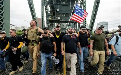  ?? Noah Berger/Associated Press ?? Members of the Proud Boys, a far-right, neo-fascist group, and other right-wing demonstrat­ors march across the Hawthorne Bridge during a rally Saturday in Portland, Ore.