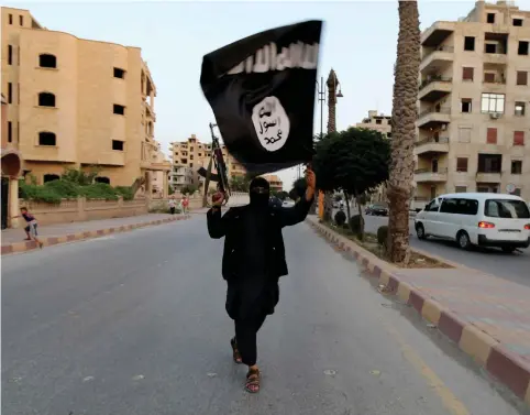  ??  ?? A MEMBER of ISIS waves the group’s flag in Raqqa recently.