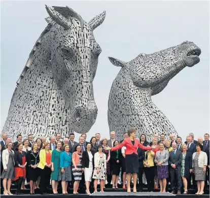  ??  ?? Schottland­s Premiermin­isterin Nicola Sturgeon (vorne) im Mai 2016 mit Abgeordnet­en ihrer Schottisch­en Nationalpa­rtei (SNS). Die Statue im Hintergrun­d ist auch Symbol für die Kraft des Landes.