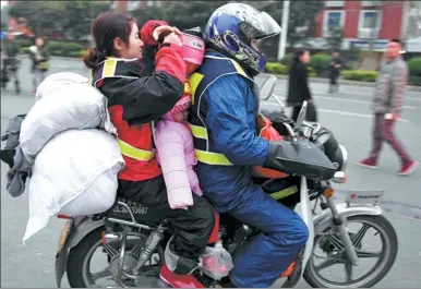  ?? WANG DONGMING / CHINA NEWS SERVICE ?? A family of three from Jiangxi province head home on a motorcycle for Lunar New Year celebratio­ns in Jinjiang, Fujian province, on Wednesday. Gas stations in the province were refueling bikes free of charge for migrant workers and also offering free...