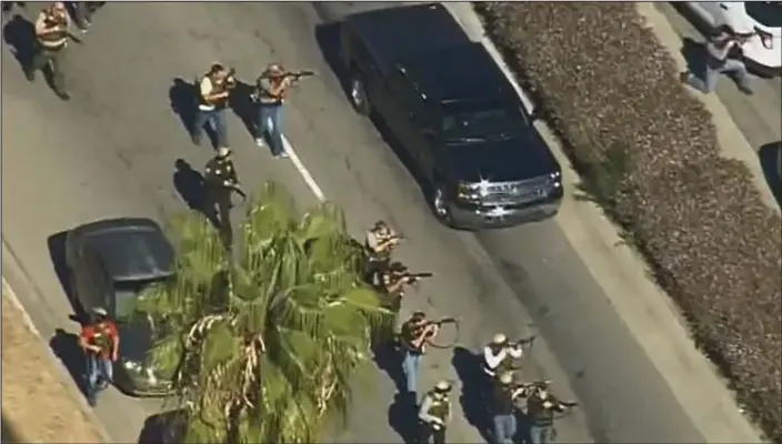  ?? ?? Rapid response: Heavily armed SWAT officers, many of them wearing body armour, train their guns on the centre in San Bernadino yesterday as they try to surround the attackers