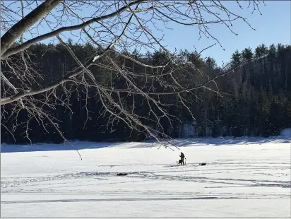  ?? PHOTOS BY LISA RATHKE — THE ASSOCIATED PRESS ?? An ice fisherman stands on the frozen Molly’s Falls Pond in Marshfield, Vt., on Sunday.