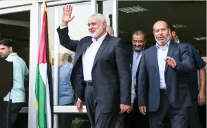  ??  ?? Ismail Haniyeh, Hamas chief, waves to journalist­s upon his arrival on the Palestinia­n side of the Rafah border crossing, in the southern Gaza Strip on Thursday. (AFP)