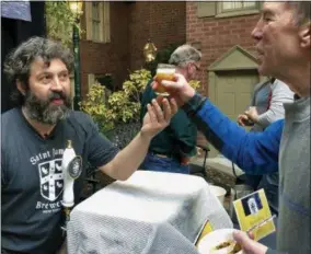  ?? MARY ESCH—ASSOCIATED PRESS ?? In this March 9, 2019photo, Jamie Adams, left, hands out a sample of his new ale called “Deep Ascent” at the New York State Craft Brewers Festival in Albany, N.Y. Adams, a former Wall Street trader who opened Saint James Brewery in Long Island nearly two decades ago, says his beer grew out of his love of scuba diving. It was brewed with yeast extracted from bottles he and fellow divers salvaged from the SS Oregon, a luxury liner from Liverpool to New York that collided with a schooner and sank off Fire Island in 1886.