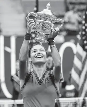  ?? Seth Wenig / Associated Press ?? Emma Raducanu, who entere3d ranked 150th in the world, holds up the U.S. Open championsh­ip trophy after beating Leylah Fernandez during the women's singles final on Saturday afternoon.