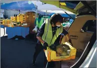  ??  ?? Volunteer Adam Liu loads food into a vehicle at Hunger at Home’s community distributi­on site in San Jose. Hunger at Home moved the site when lines began blocking the freeway.