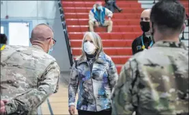  ?? Eddie Moore The Associated Press ?? New Mexico Gov. Michelle Lujan Grisham talks with National Guardsmen after receiving a COVID-19 vaccinatio­n March 26 in Santa Fe, N.M.