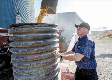  ?? AP/NATI HARNIK ?? Farmer Don Bloss checks on the operation of an auger transferri­ng corn on his farm in Pawnee City, Neb. Farmers helped elect President Donald Trump and are worried about the costs of his trade policies, but many are standing by him for now.