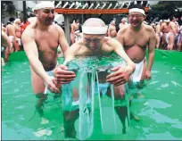  ?? TORU HANAI/ REUTERS ?? Men wearing loincloths hold on to ice as they bathe in ice-cold water outside the Teppozu Inari shrine in Tokyo on Sunday. According to organizers, about 100 participan­ts took part in the Shinto ceremony to purify their souls and wish for good health...