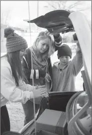  ?? NWA Democrat-Gazette/CHARLIE KAIJO ?? Former Bentonvill­e High Key Club and now University of Arkansas student Hailey Swalve of Bentonvill­e loads boxes of food Monday into the trunk of a car for Norma Jackson and Joshua Schmitz, 12, of Gentry (from left) during the Guy Wilkerson food basket giveaway.