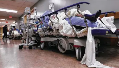  ?? Mario Tama / Getty Images ?? Patients lie on stretchers in a hallway Tuesday in the overloaded Providence St. Mary Medical Center in Apple Valley amid a surge in COVID-19 cases traced to holiday gatherings. Hospitals hope to avoid rationing care to patients more likely to survive.