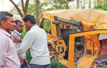  ?? AP ?? People gather around the wreckage of a school van that was hit by a train at an ungated railroad crossing, near Kushinagar, in Uttar Pradesh, yesterday.