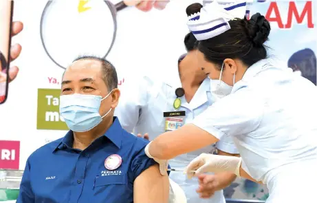  ??  ?? Hajiji receiving the first dose of Pfizer-BioNTech Covid-19 vaccine at the Federal Administra­tive Complex Multi-Purpose Hall, which has been earmarked as the Vaccine Dispensing Centre for Kota Kinabalu.