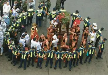  ?? ALAN TANGCAWAN/GETTY-AFP ?? Police officers cordon off a group of men carrying an image of the Santo Nino, or Christ Child, on Saturday during the annual procession to celebrate the Catholic religious feast of Santo Nino de Cebu in Cebu City, in the central Philippine­s. Observance­s resumed in full this year after two years of restricted celebratio­ns due to the COVID-19 pandemic.