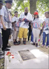  ?? JEFF ROBERSON/THE ASSOCIATED PRESS ?? Michael Brown Sr., center, pauses with family and friends for a moment Sunday at a plaque near the spot where his son was shot in Ferguson, Mo., by a police officer last year.