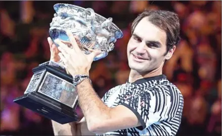  ??  ?? Roger Federer celebrates with the trophy after his victory over Rafael Nadal in the men’s singles final on day 14 of the Australian Open in Melbourne yesterday.