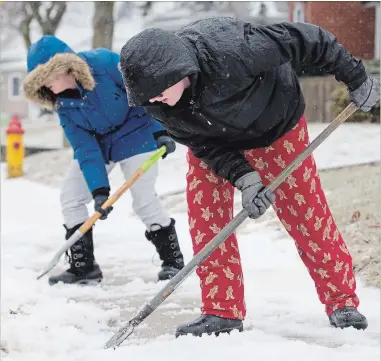  ?? PETER LEE WATERLOO REGION RECORD ?? Nick Stasios and twin sister Mattie scrape the sidewalk outside their home on Stirling Avenue in Kitchener Wednesday.