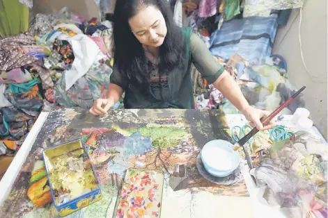  ?? — AFP photos ?? Thuc working on an artwork made from fabrics in her home studio in Hanoi.
