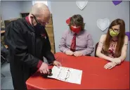  ?? ?? Erik Conklin, and Jackie Bauman watch as Hon. Eric J. Taylor puts the offical seal on their marriage certificat­e. At Magisteria­l District Court 23-2-02in West Reading, PA Monday February 14, 2022where Magisteria­l District Judge Hon. Eric J. Taylor spent Valentine’s Day marrying couples.