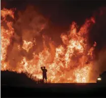  ?? AP PHOTO/NOAH BERGER ?? In this Dec. 6, 2017, file photo, a motorist on Highway 101 watches flames from the Thomas Fire, the largest wildfire on record in California, leap above the roadway north of Ventura. On Thursday, Gov. Jerry Brown signed an executive order that aims to...