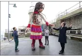  ?? (AP/PA/Gareth Fuller) ?? Actor Jude Law (right) greets Little Amal, an 11½-foot-tall puppet of a 9-year-old Syrian girl, as it arrives at Folkestone Beach in England on Tuesday.